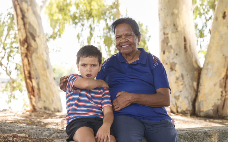 Indigenous boy and female elder sitting on a log