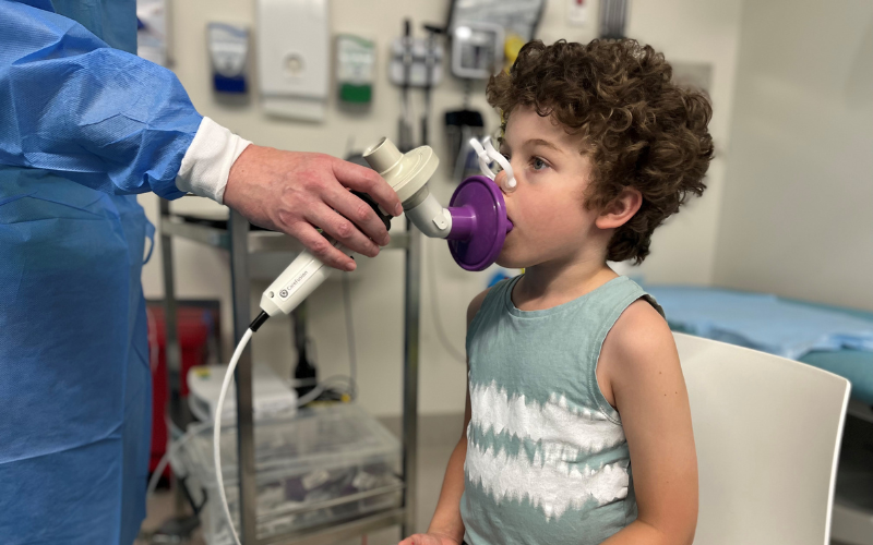 Curly haired boy doing a lung function test